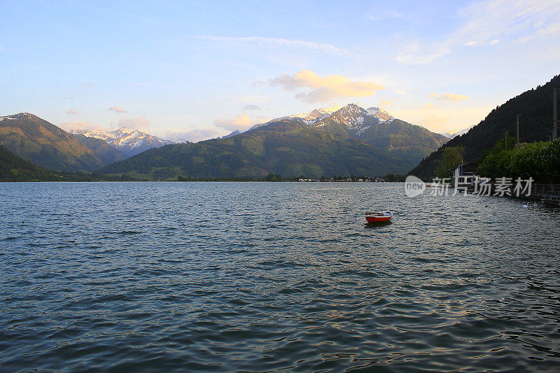 孤独的小船在夕阳下漂浮在美丽的泽勒湖上-泽尔am See, Tirol Austria Salzburger land, Austria